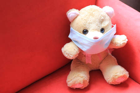 Teddy bear with protection mask clinical use for covid pandemic, red backgroundの写真素材