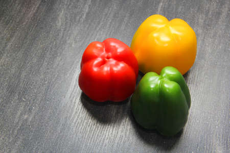 colorful vegetables and peas, yellow, green and red bell peppers on vintage gray wooden background