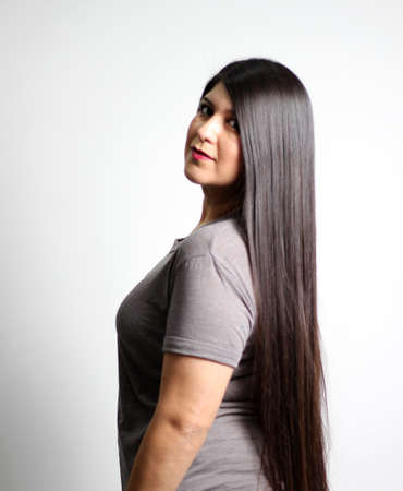 Overweight Latin young adult woman shows how silky and shiny her black hair is, very long, straight,...