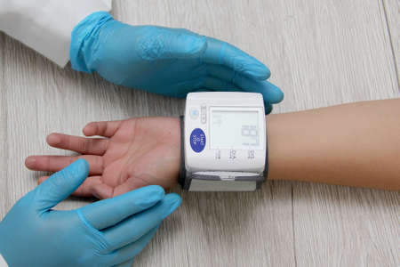 Doctor use blood pressure monitor with patient to diagnose hypertension due to kidney disease,...