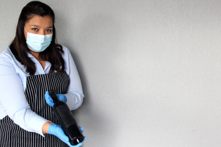 Latin woman sommelier with red wine, crystal glasses working with protection mask and latex gloves, new normal covid-19の写真素材