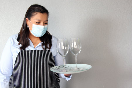 Latin woman sommelier with red wine, crystal glasses working with protection mask and latex gloves, new normal covid-19の写真素材