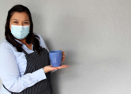 Latin chef woman with protection mask and coffee cups, new normality covid-19 in cafes and restaurantsの写真素材