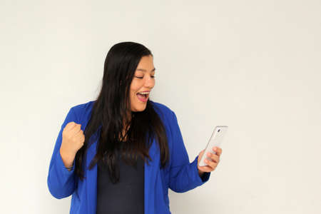 Latin adult woman with straight black hair and a blue jacket sends and receives messages from her...