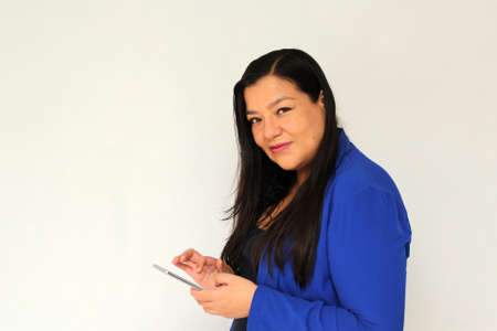 Latin adult woman with straight black hair and a blue jacket sends and receives messages from her cell phone very excited and happy makes purchases online in appの写真素材