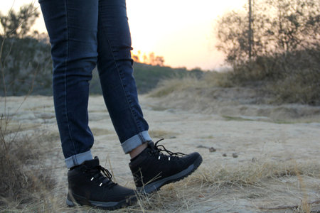 Legs with denim pants and black hiking boots in the middle of the field walk, pose, play, explore, discover and live in freedomの写真素材