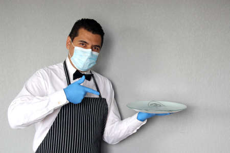 Latino chef serving coffee and food, working with latex gloves and face masks, new normal for the covid-19 virusの写真素材