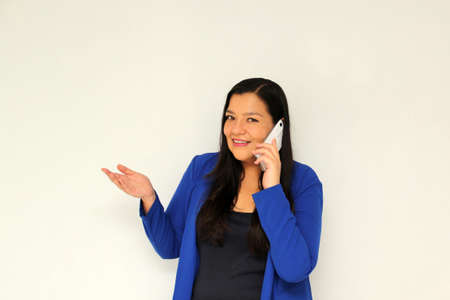 Adult latin woman over isolated white background with cell phone in victory position shows happy and excitedの写真素材