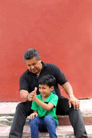 Single latino grandfather and grandchild play and have fun together spending quality family time on Father's Day celebrating victory with hugs and kissesの写真素材