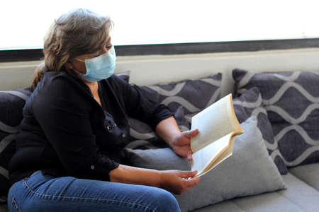 latin grandmother with protection mask reading book in waiting room