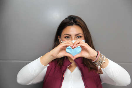 Latin young woman with protection mask and box of chocolates. hearts. Valentine's Day