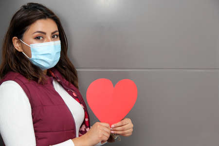 Latin young woman with protection mask and box of chocolates. hearts. Valentine's Day