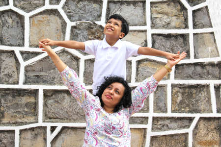 Dark-haired Latin mom and son play and have fun together spend quality time playing in a park...