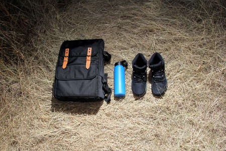 Backpack, flask and boots for hiking in the mountains at sunrise, equipment for extreme outdoor...