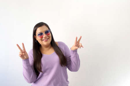 Latin adult woman with heart-shaped sunglasses shows enthusiasm for February and celebrate...