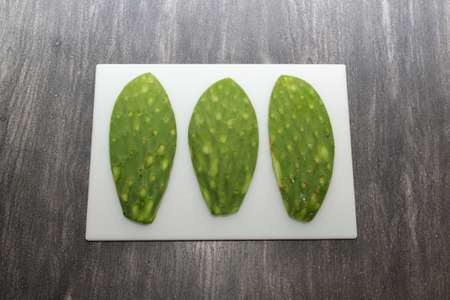 Raw spineless fresh green Mexican nopales on a chopping board and knife ready to cookの写真素材
