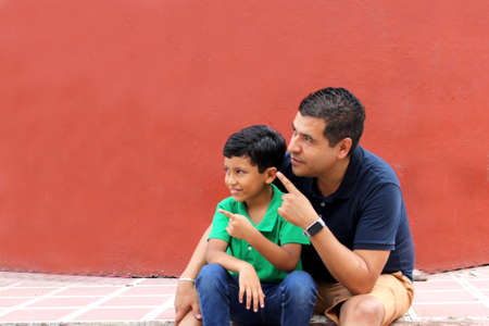 Single dad and dark-haired Latino son play and have fun together spending quality family time on Father's Day celebrating victory with hugs and kissesの写真素材