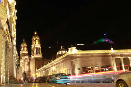 Colonial style streets illuminated at night in the city of Zacatecas in Mexico with the cathedral, basilica of the downtown of the state capital with the colored Cerro de la Bufaの写真素材