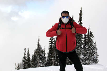 Latin adult man arrives in Canada and discovers the snowy mountains with a face mask due to the...