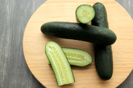 Fresh, green cucumbers on a chopping board with knife are prepared for a nutritious salad or juice...