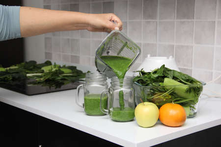 Serve green juice in mason jar just made in kitchen blender with ingredients like cucumber, chard,...