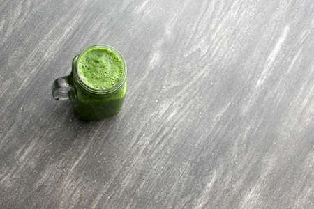 Green juice served in a mason jar with vegetables such as cucumber, chard, spinach, lemon and fruits...
