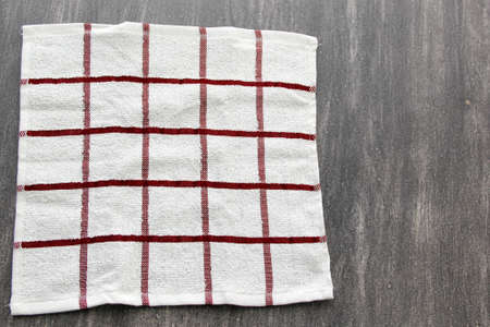White cloth napkin with red lines to use with hot bread, tortillas, toast or cookies to accompany the meal on the gray wooden tableの写真素材