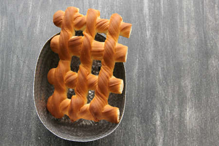 Fresh, fresh, fluffy sweet bread in the shape of a grate on a wooden table on a napkin to keep warm
