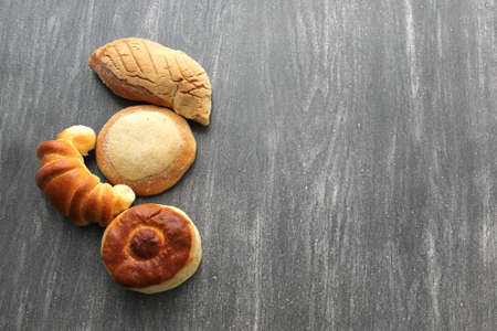 Mexican sweet bread such as biscuit, croissant, grating and fluffy worm, fresh, freshly made at home on a wooden table with napkin and basketの写真素材