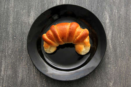 Delicious, fresh, fluffy freshly made sweet croissant bread ready for breakfast with hot coffee on a wooden board on a colored napkinの写真素材