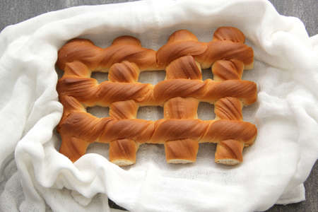 Fresh, fresh, fluffy sweet bread in the shape of a grate on a wooden table on a napkin to keep warm