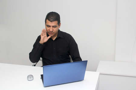 Latino adult man speaks Mexican sign language with a deaf person through a laptop in a video call