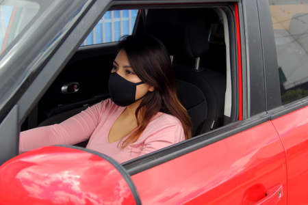 latin woman driver with protection mask in vehicle interior, new normal when drivingの写真素材