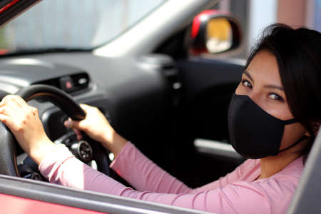 latin woman driver with protection mask in vehicle interior, new normal when drivingの写真素材