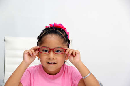 Brunette Latin girl shows her red glasses to see better because she has myopia and astigmatismの写真素材