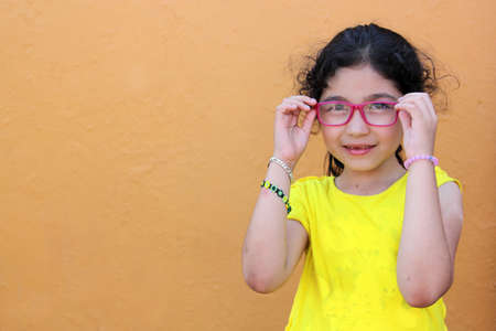 Hispanic 6-year-old girl shows her red glasses that she wears because she has astigmatism and myopia...
