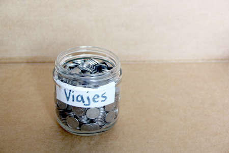 silver coins in a glass jar with travel message new year's resolution, better finances and savings
