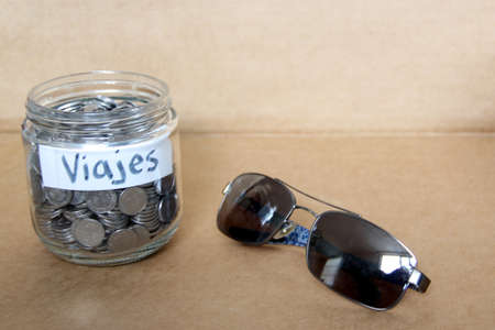 silver coins in a glass jar with travel message new year's resolution, better finances and savings