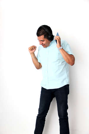 Latin adult man uses his wireless headphones and cell phone to listen to music, dance, relax and...