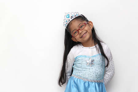Poor 4-year-old Latin brunette girl is dressed as a happy princess with her costume to go to a children's party and feel strong and empoweredの写真素材