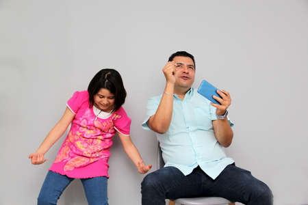 Hispanic Latino dad and daughter play, dance, surprise, enjoy, taking selfies using the cell phone...