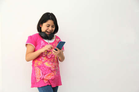 10-year-old Hispanic girl listens to music on her headphones connected to her cell phone dances, sings and enjoys the rhythm happy and excitedの写真素材