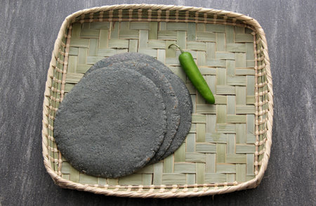 Fresh, delicious, freshly made blue crust tortillas in basket, cutting board and red napkin with...