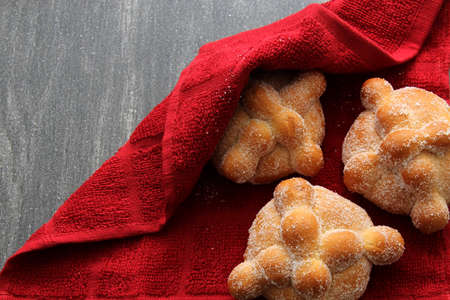 Hot freshly baked Mexican bread of the dead under a red tablecloth for the traditional feast of the...