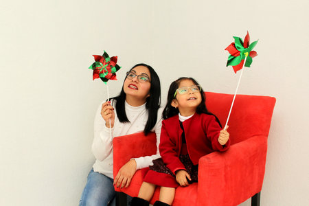 Latina mom and daughter with Christmas ornaments and decorations show their happiness and excitement...