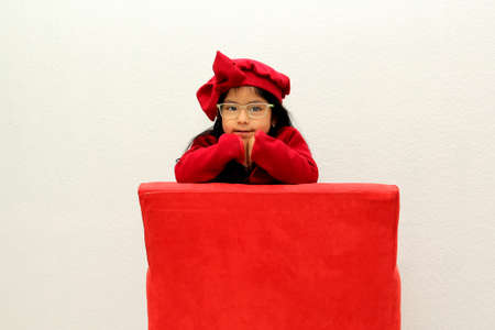 Little Latin girl with glasses dressed very elegantly for a party with a red hat is very happy and...