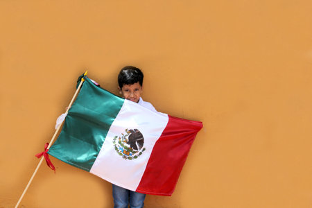 Latin Mexican boy of 8 years shows the flag of Mexico proud of his culture and tradition celebrates the national holidays of September 15 and Cinco de Mayoの写真素材