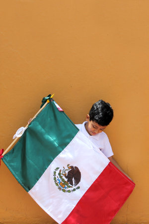 Latin Mexican boy of 8 years shows the flag of Mexico proud of his culture and tradition celebrates the national holidays of September 15 and Cinco de Mayoの写真素材