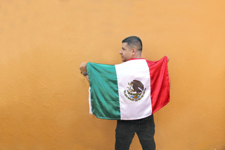 Latin Mexican adult man shows the flag of Mexico proud of his culture and tradition celebrates the national holidays of September 15, Cinco de Mayo and football soccerの写真素材