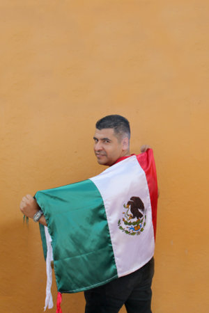 Latin Mexican adult man shows the flag of Mexico proud of his culture and tradition celebrates the national holidays of September 15, Cinco de Mayo and football soccerの写真素材